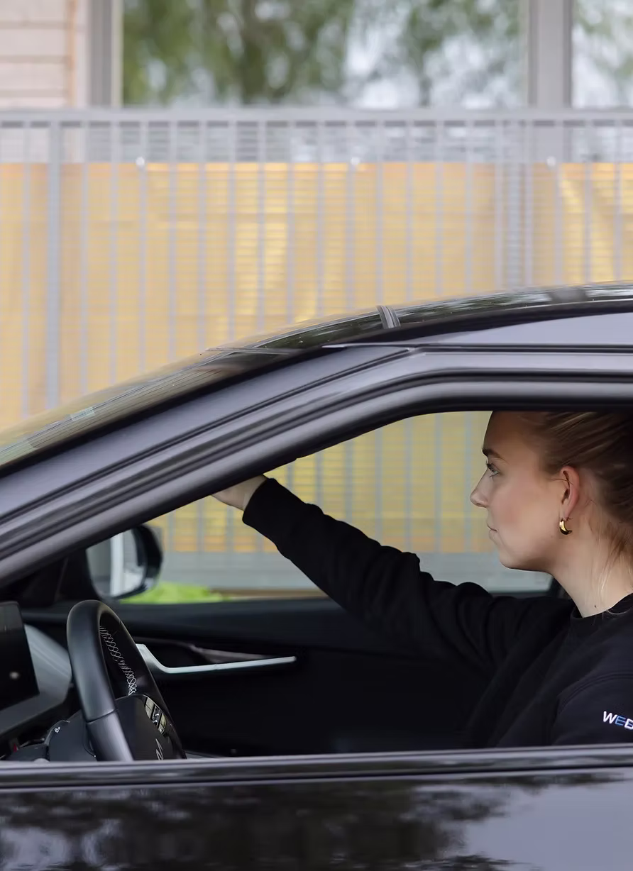 WeDrive-förare i märkeströja bakom ratten med armen på den nedvevade rutan